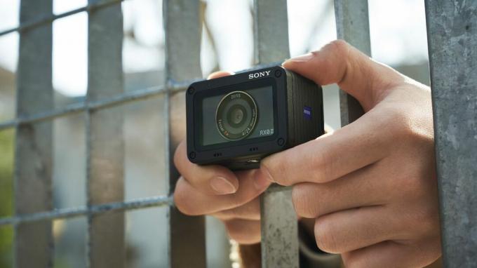Pregled Sony RX0 II: oseba drži kamero skozi palice jeklene ograje, da snema